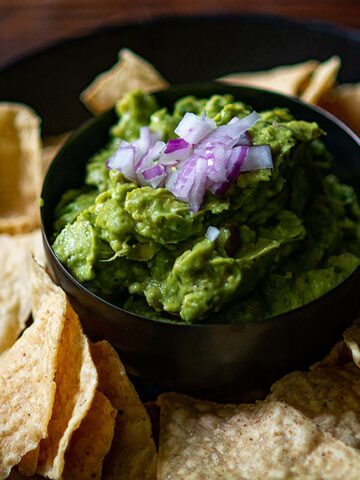 Guacamole served with tortilla chips and topped with red onions.