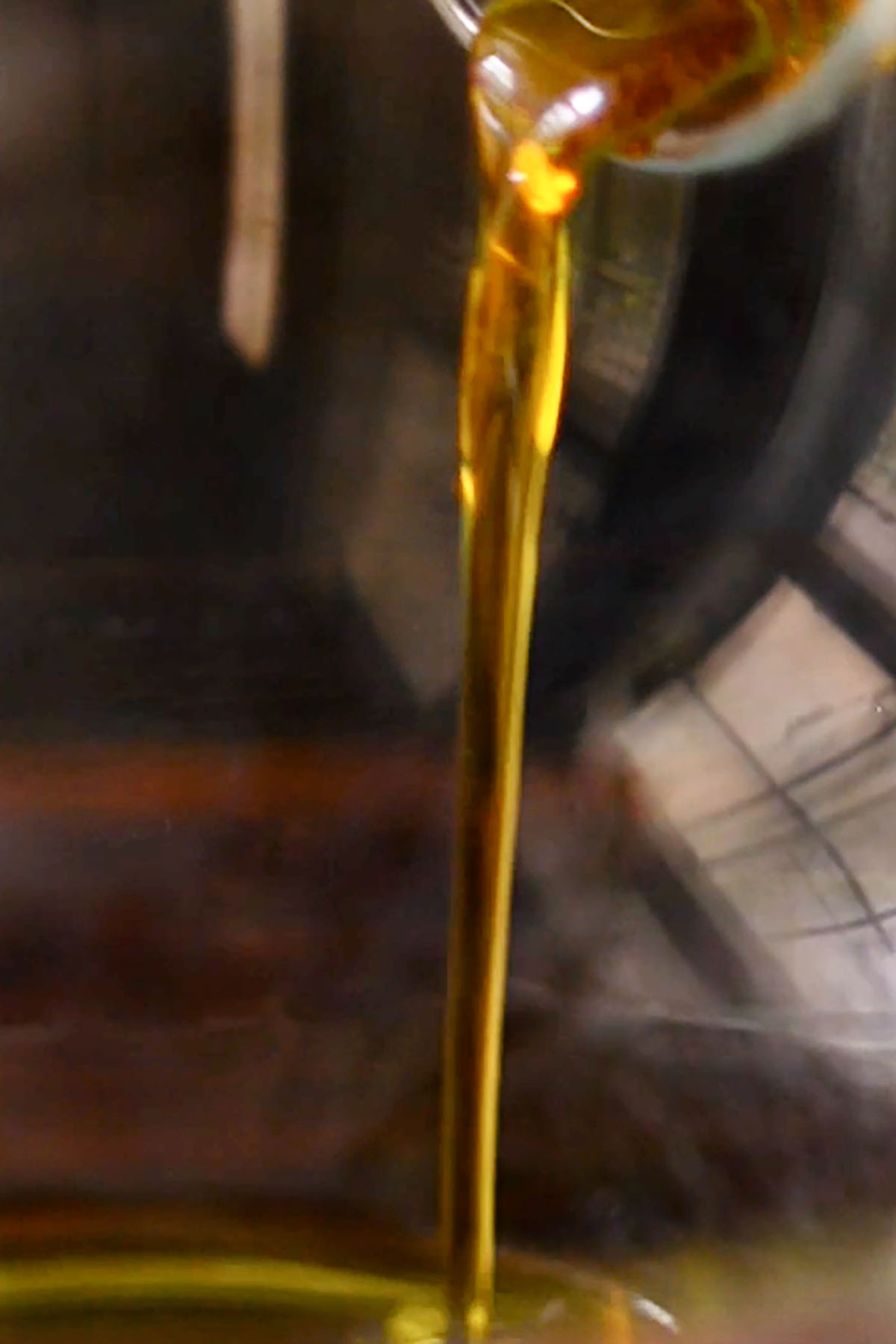 Maple syrup being added to a glass mixing bowl.