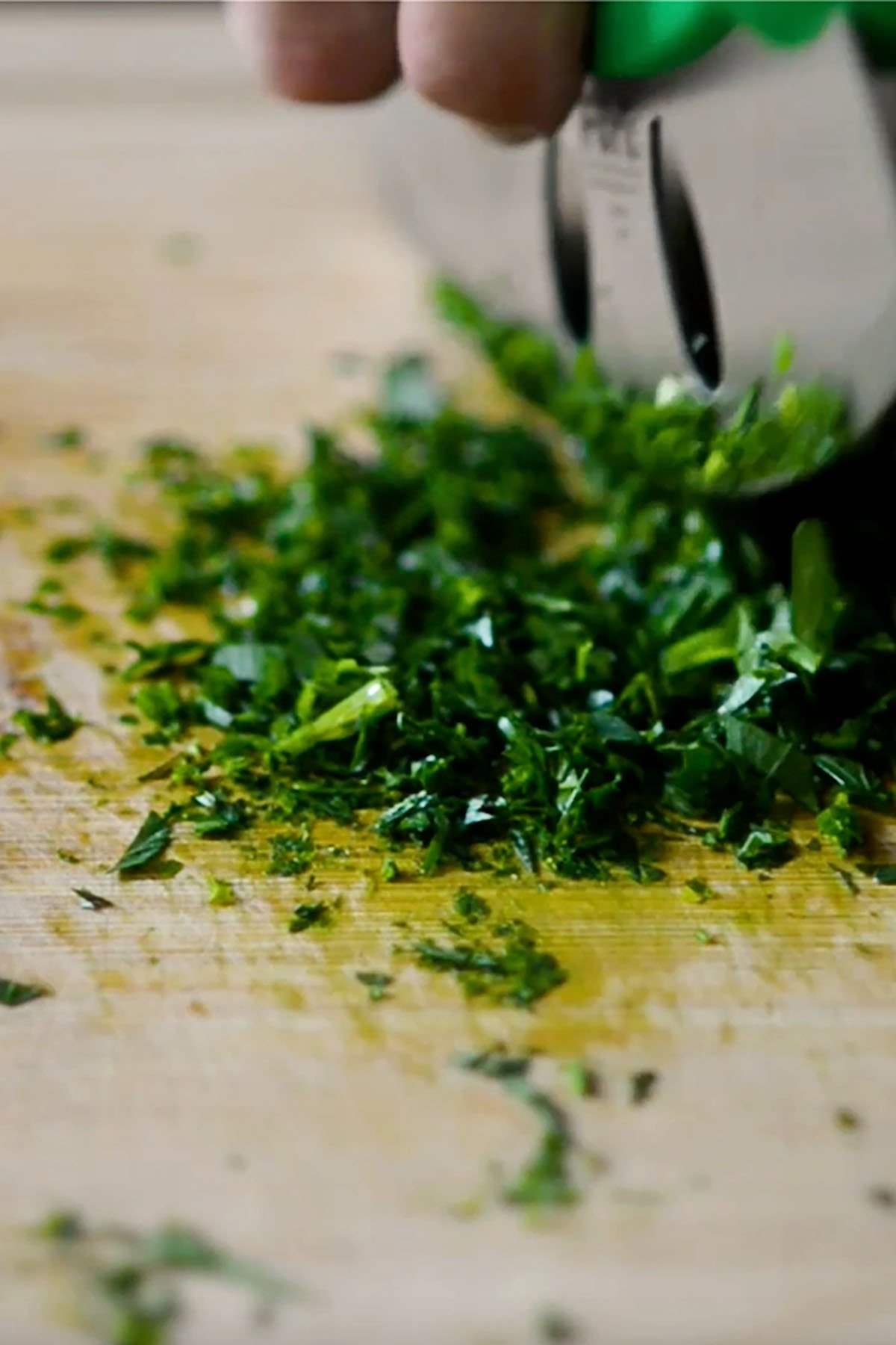 Fresh herbs chopped on a wooden cutting board.