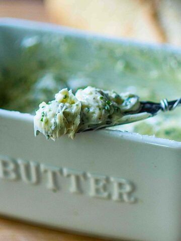 Garlic Butter served in a butter dish with a spreader and loaf of Italian Bread.