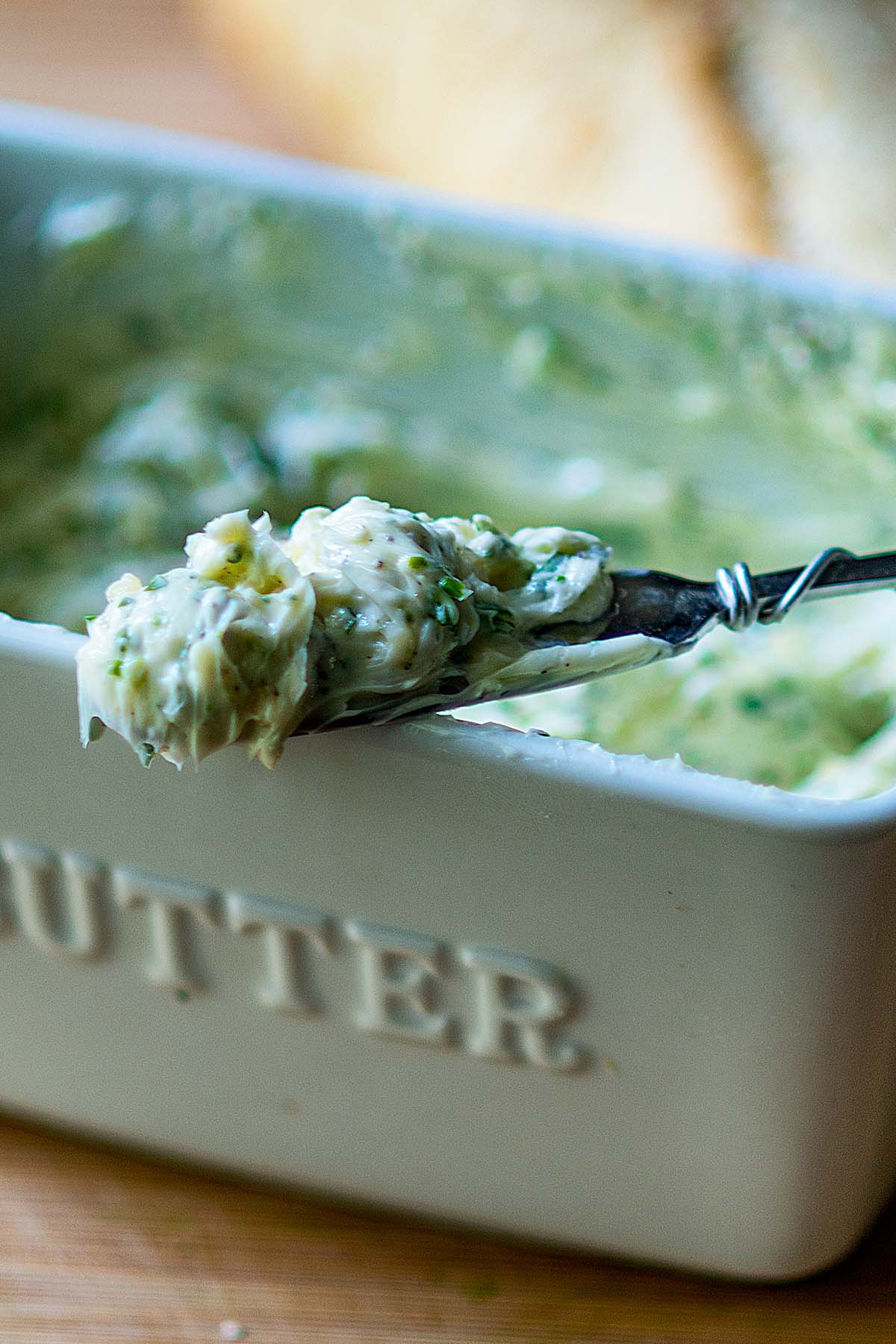 Garlic butter served from a butter dish and on a spreader.