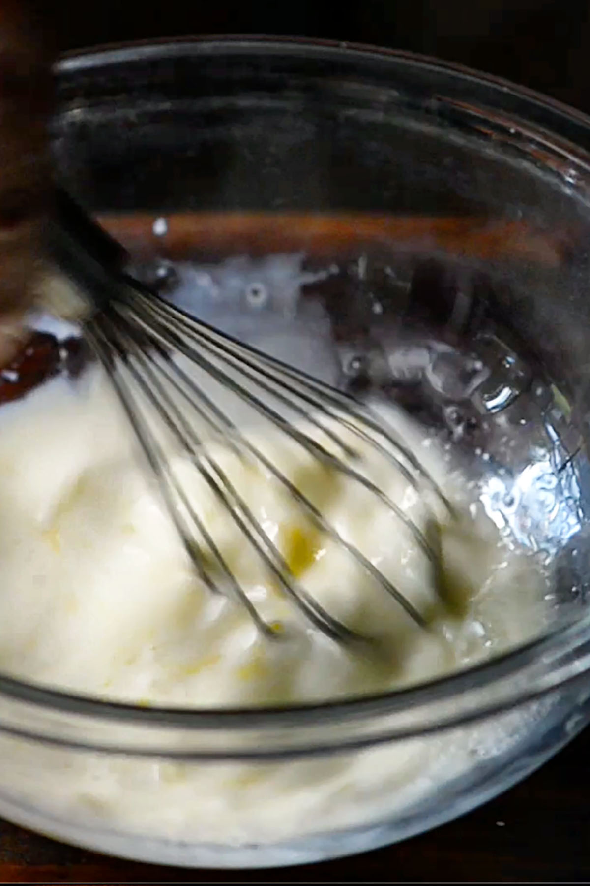 Pancake batter being whisked in a glass mixing bowl.