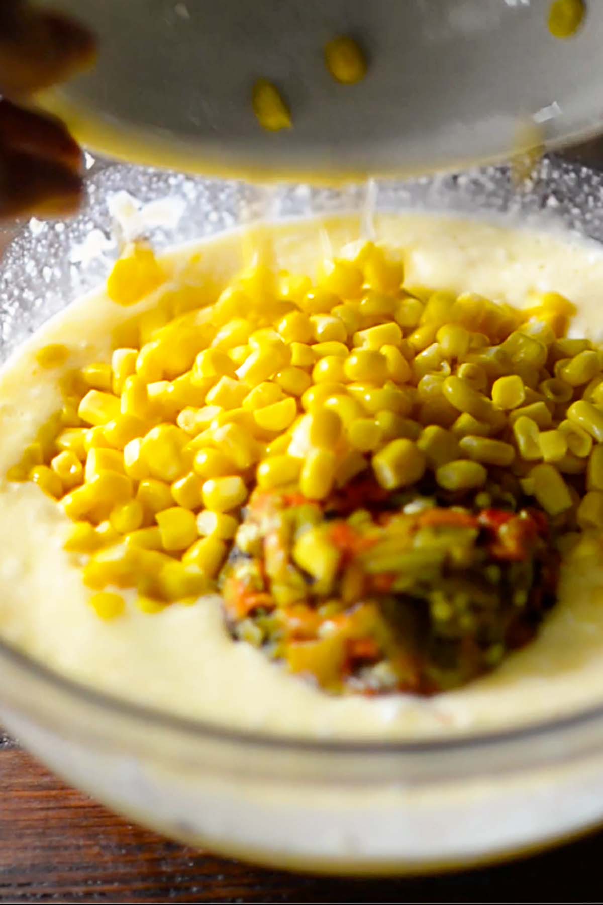 Cream corn and hatch chiles being added to a bowl.