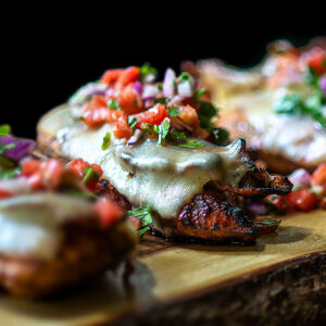 Sous Vide Grilled Monterey Chicken Breasts Served with Pico de Gallo on a live edge wooden platter.