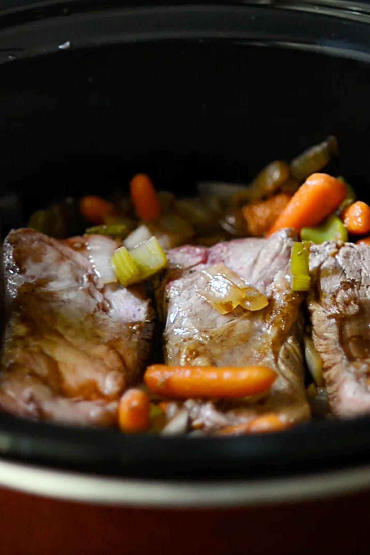 Beef short ribs combined with mixed vegetables in a crock pot.