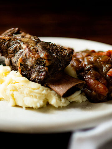 A slow cooker short rib served over mashed potatoes with braised onions and carrots.