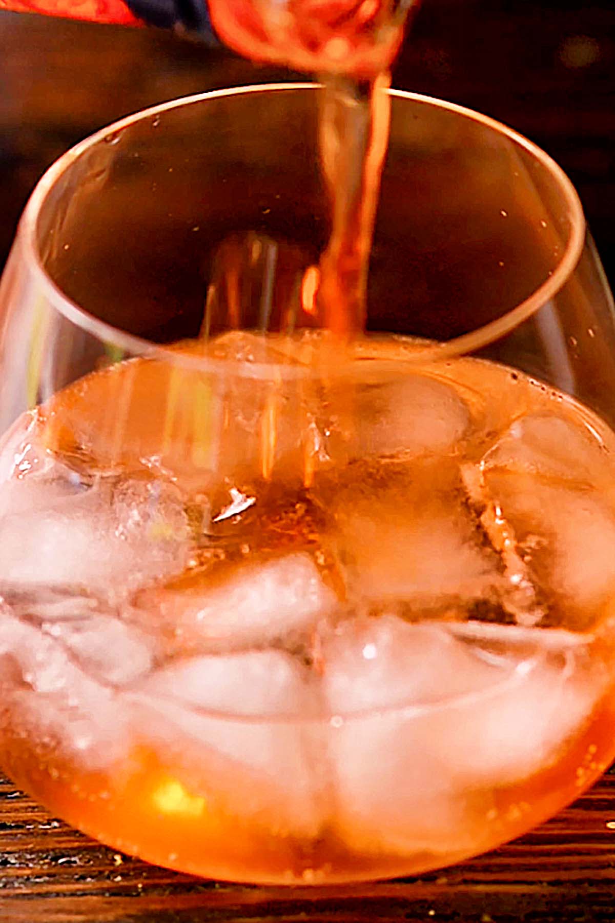 Aperol being poured into a wine glass of ice and Prosecco.