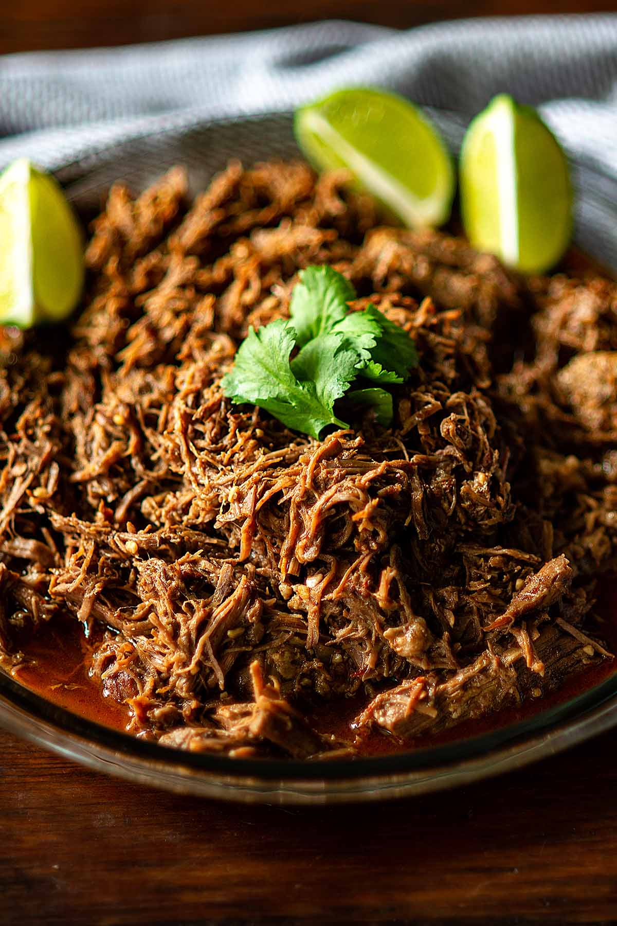 Barbacoa served with cilantro and lime wedges.