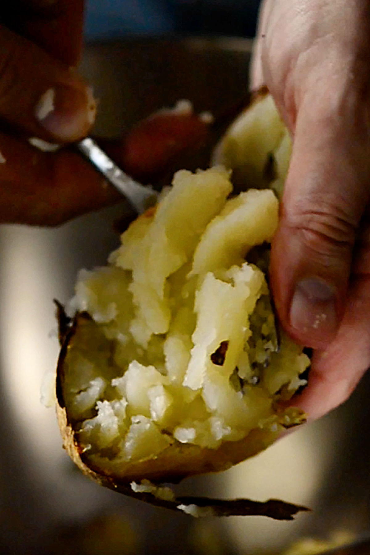 Baked potato being scooped out with a spoon.