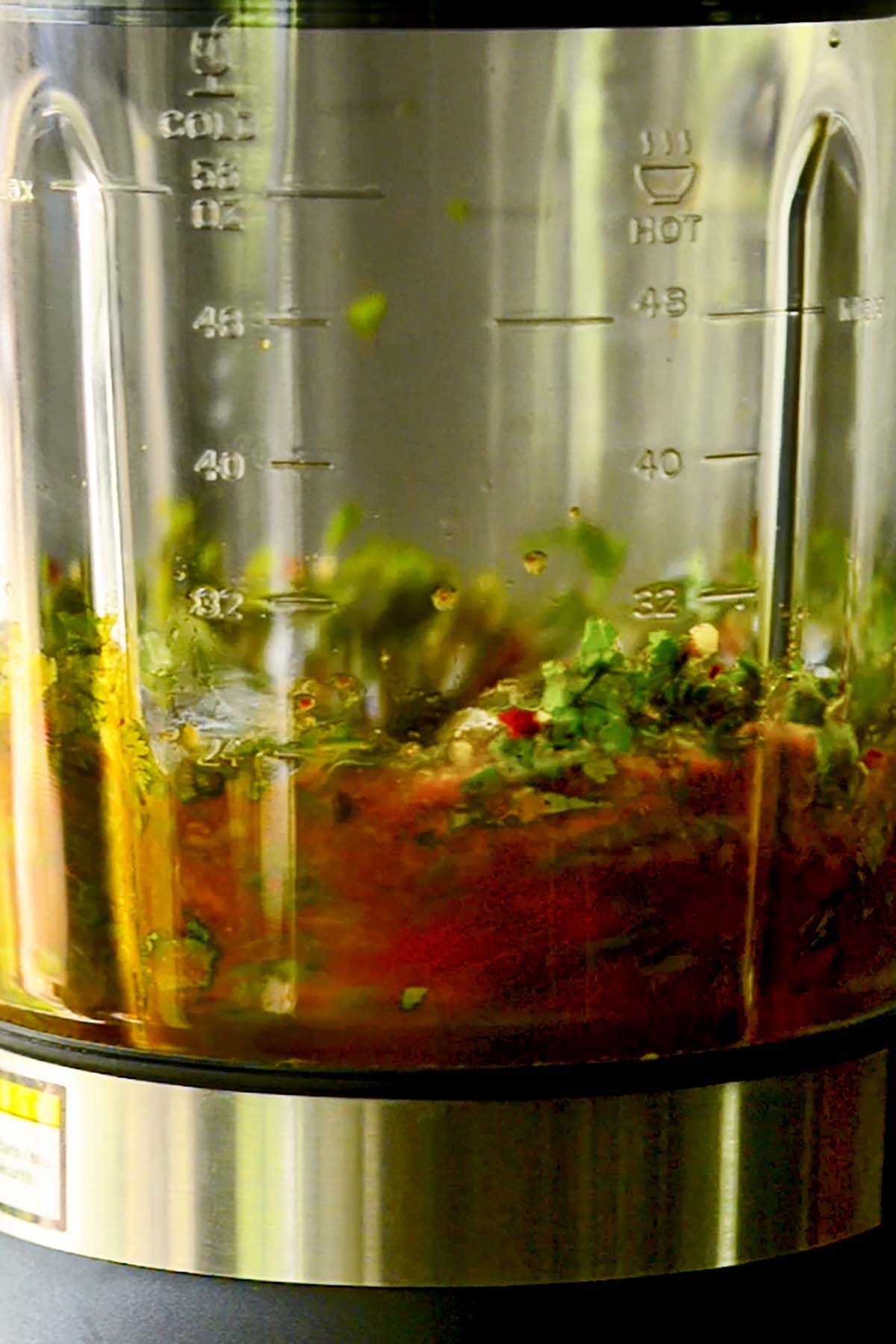 Red chimichurri sauce being gently blended in a blender.
