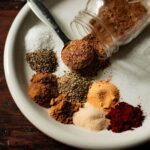 Herbs and aromatics spooned onto a plate with a spoonful of mixed carnitas seasoning.