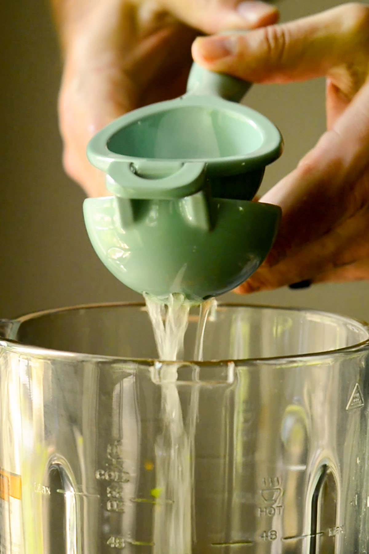 Fresh lemon juice being squeezed into a blender.