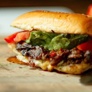 A Churrasco Italiano Sandwich served on a wood cutting board.