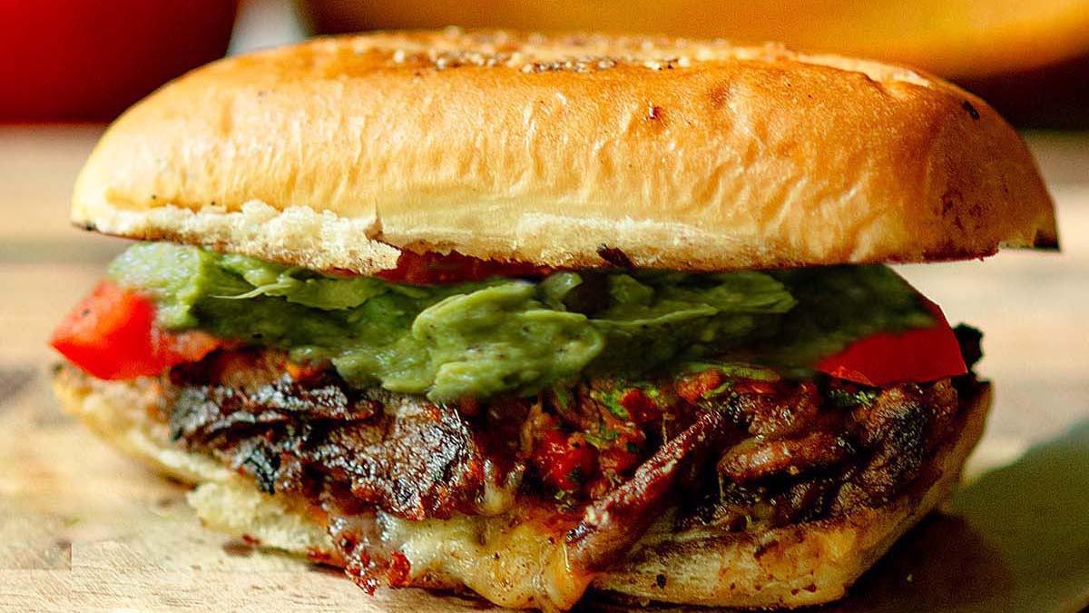 A Churrasco Italiano Steak Sandwich on a wood cutting board.