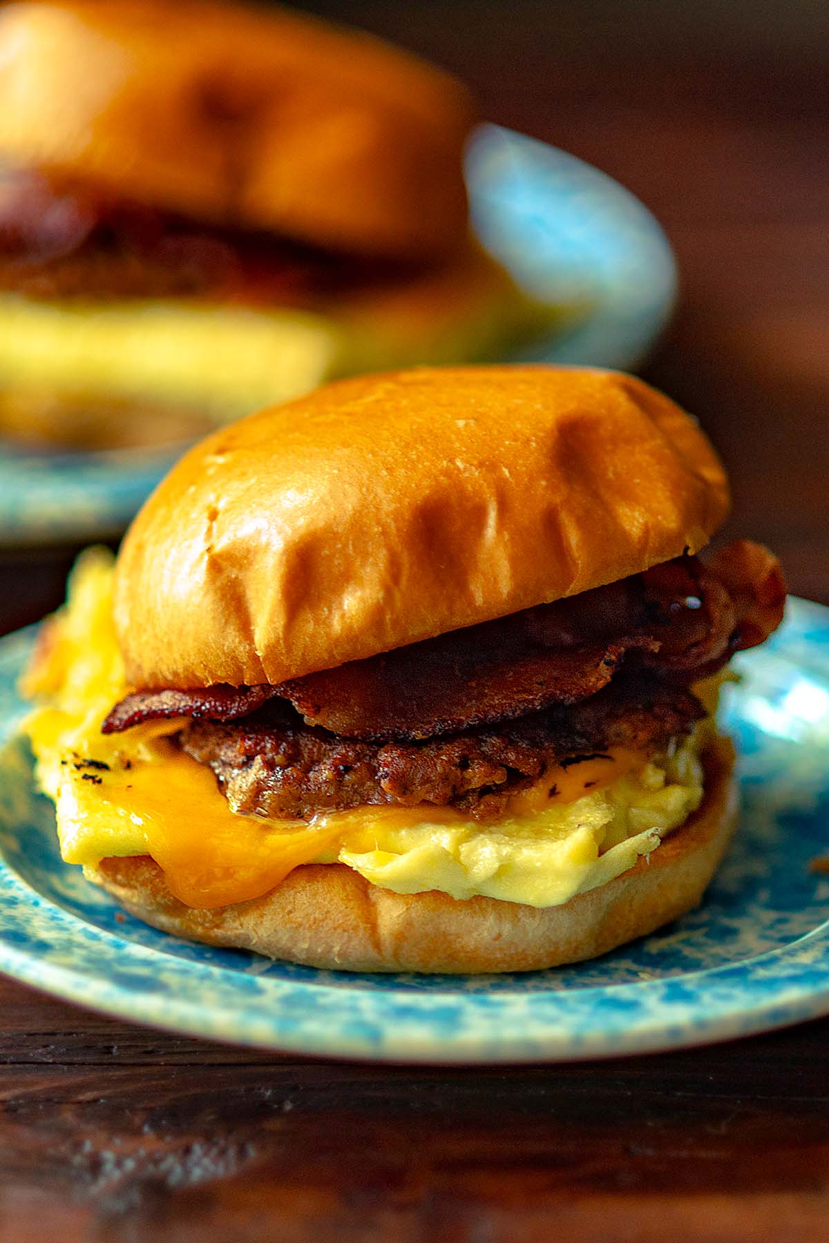 A Breakfast sandwich with sausage, bacon, egg, and cheese on a brioche bun.