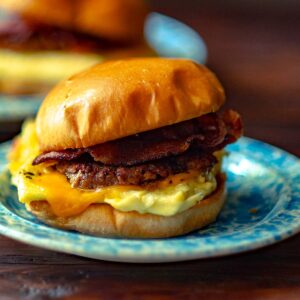 A breakfast sandwich with bacon, sausage, egg and cheese on a brioche bun.