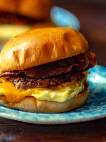 A breakfast sandwich with bacon, sausage, egg and cheese on a brioche bun.