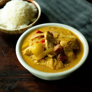 Thai Yellow curry served in a bowl with a bowl of white rice on the side.