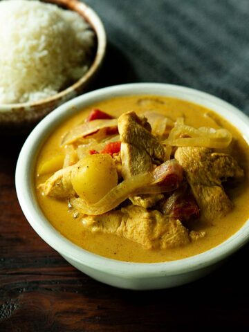 Thai Yellow curry served in a bowl with a bowl of white rice on the side.