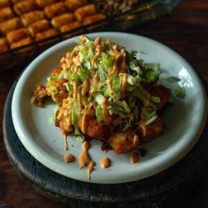 Big Mac Tater Tot Casserole served and topped with shredded lettuce and a decorative drizzle of Big Mac Sauce.