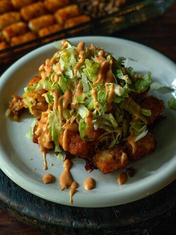 Big Mac Tater Tot Casserole served and topped with shredded lettuce and a decorative drizzle of Big Mac Sauce.