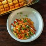 Buffalo Chicken Tater Tot Casserole Served on a white plate drizzled with buffalo sauce, buttermilk ranch, and topped with sliced green onions.
