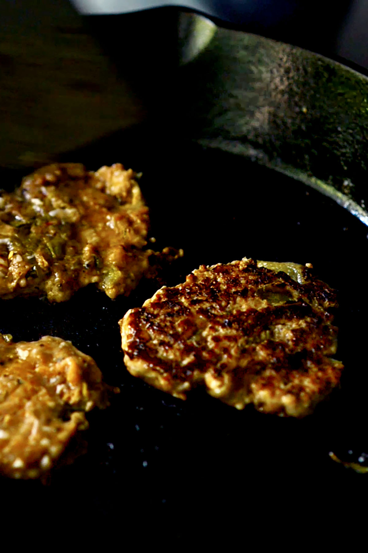 Chicken Breakfast Sausage Patties being cooked in a cast iron skillet.