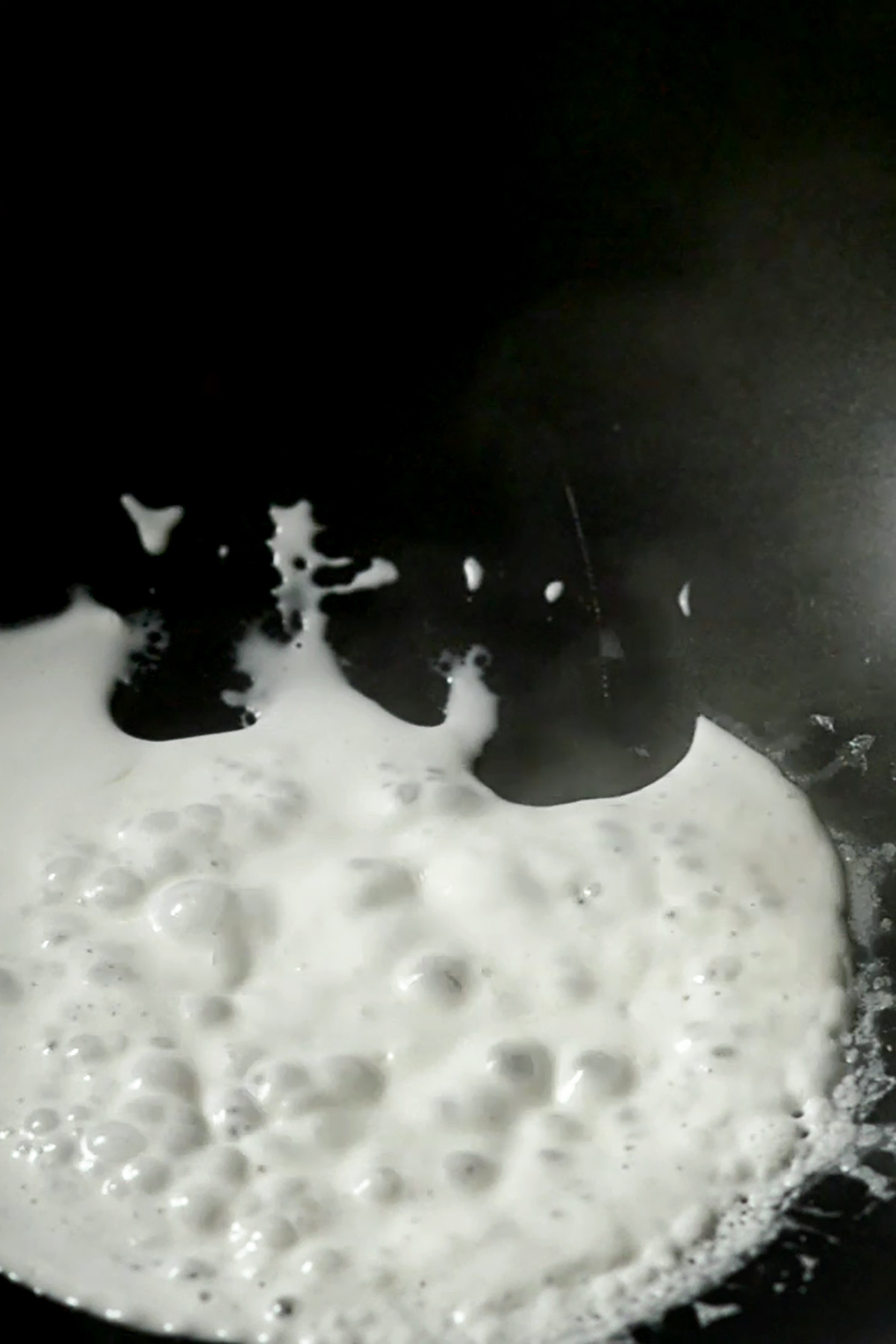 Coconut milk boiling in a wok.