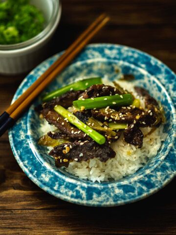 Green Chile Beef Stir Fry served over rice with green onion and topped with roasted sesame oil and sesame seeds.