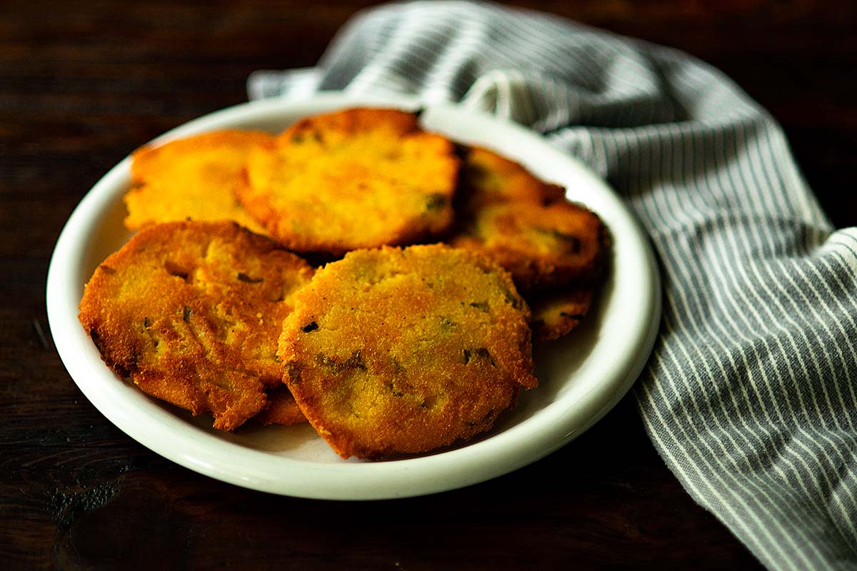 Hot water cornbread stacked on a plate served family style.