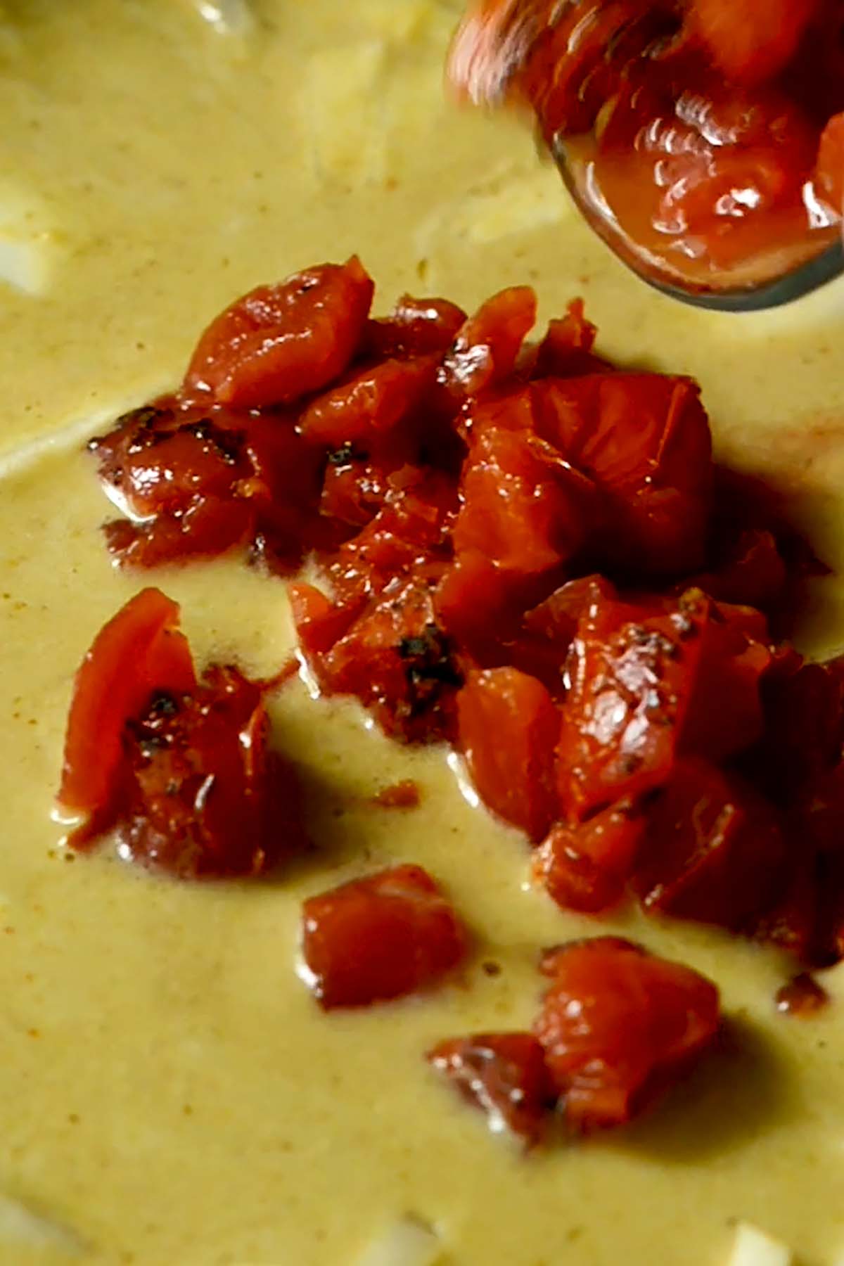 Roasted Tomatoes added to Thai Yellow Curry in a Wok.