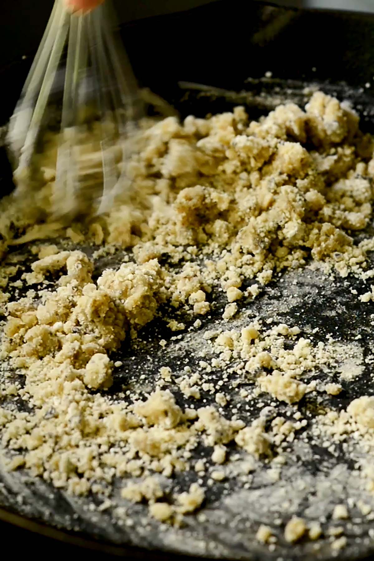 Flour being whisked into oil in a cast iron skillet for a smothered oxtail roux.