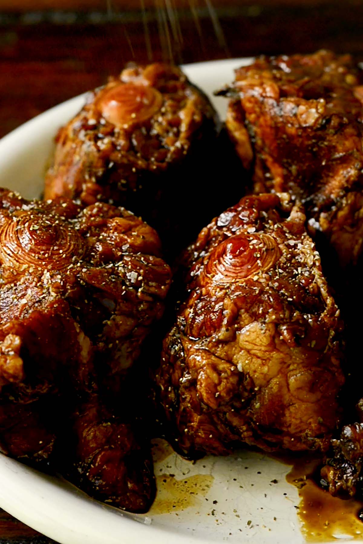 Oxtails on a plate covered in Worcestershire sauce and browning seasoning.