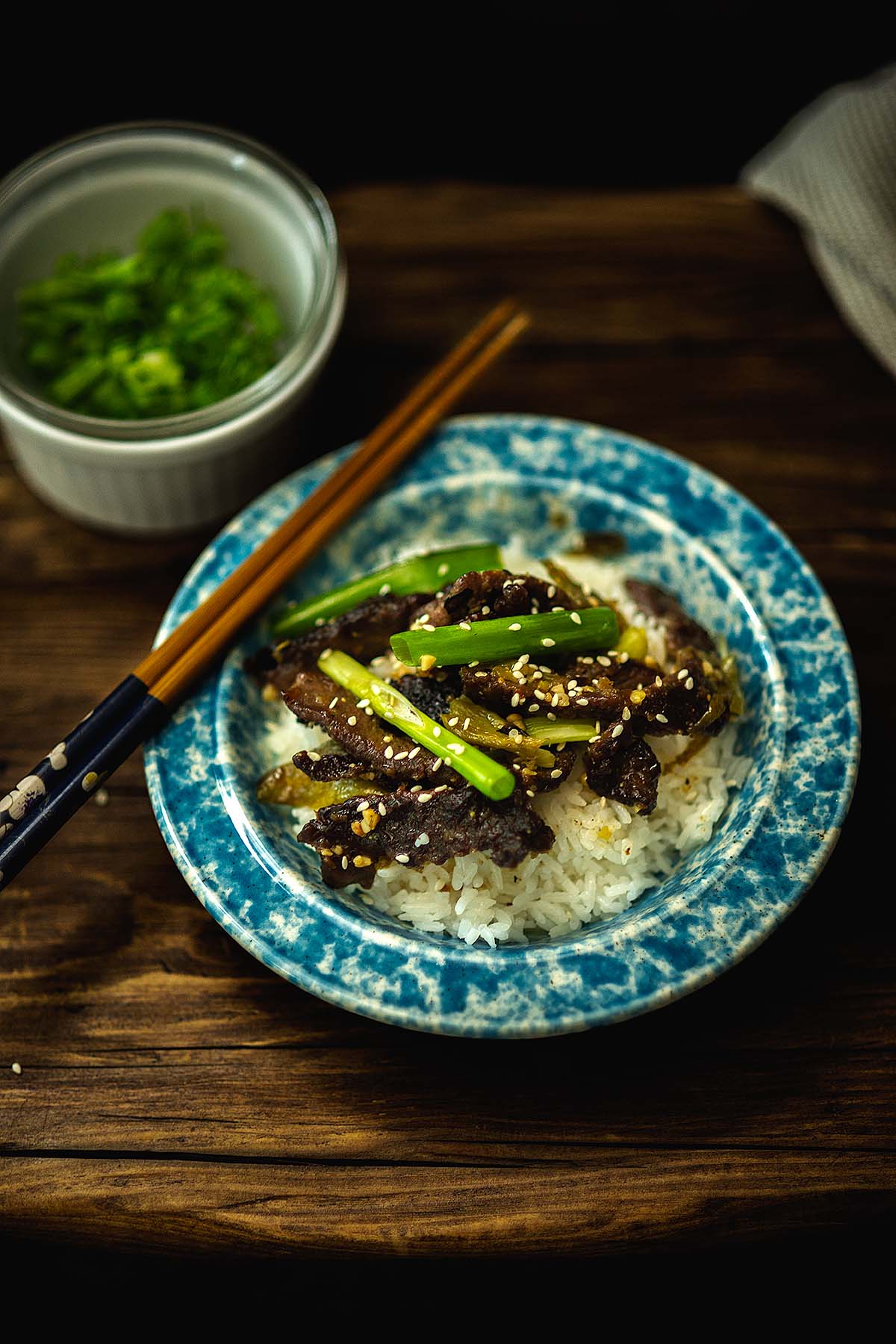 Green Chile Beef Stir Fry served over rice with green onion and topped with roasted sesame oil and sesame seeds.