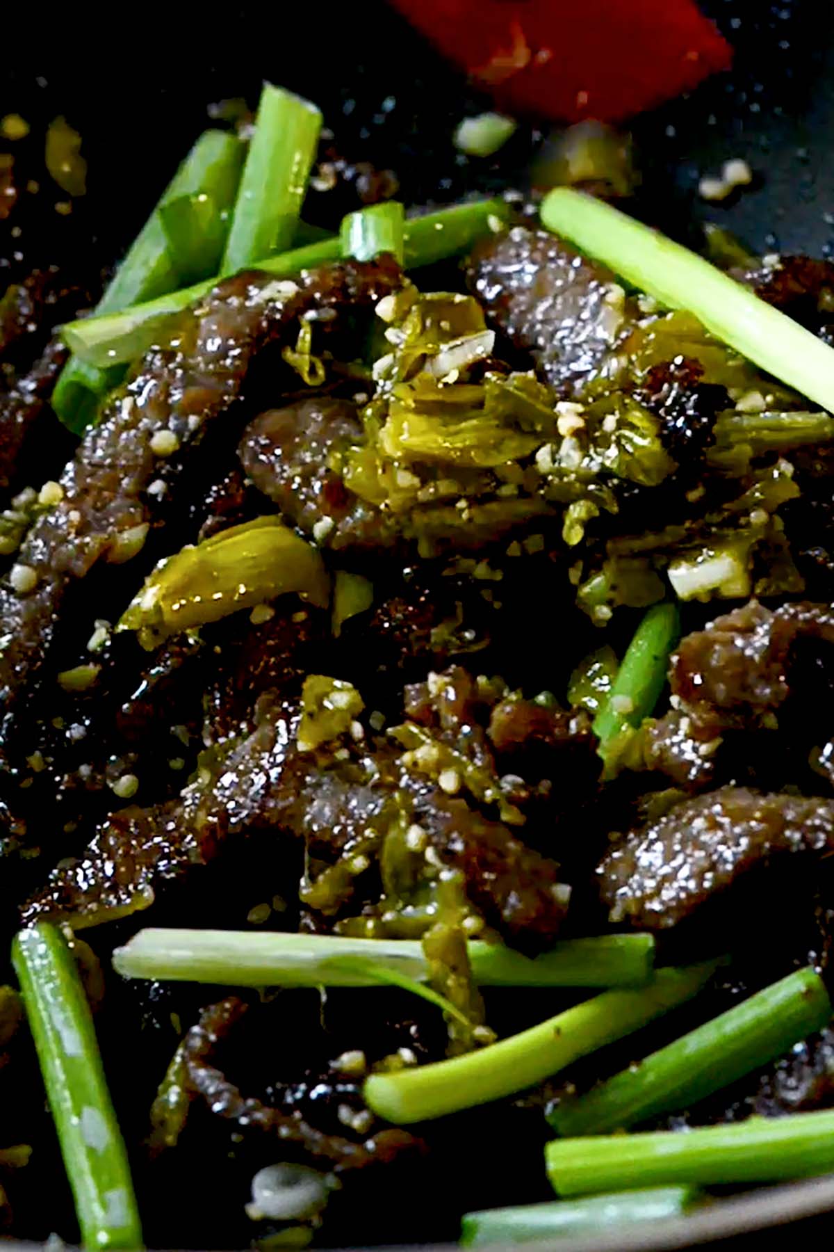 Green Chile Beef Stir Fry in a wok with large pieces of green onions.