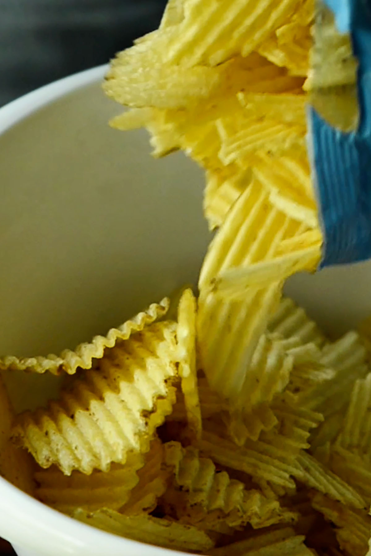 Potato chips being added to a mixing bowl to be crunched up for an old fashioned tuna noodle casserole topping.