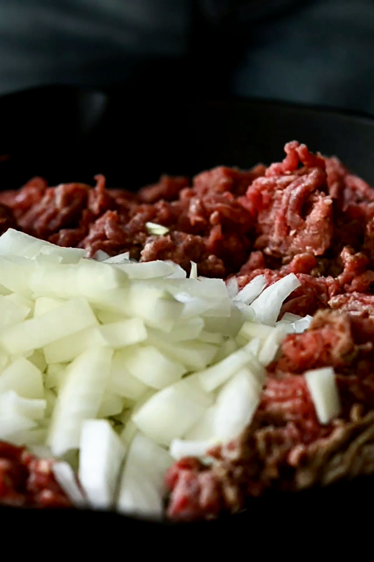 Ground beef and diced onions cooking a cast iron skillet.