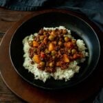 Filipino Picadillo served over rice in a deep dish black plate.