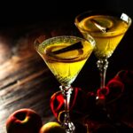Apple Cider Martini served in a crystal martini glass and garnished with slices apple rings and a cinnamon stick.