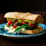 A burrata sandwich with fresh herbs, tomatoes, avocado, and balsamic glaze.