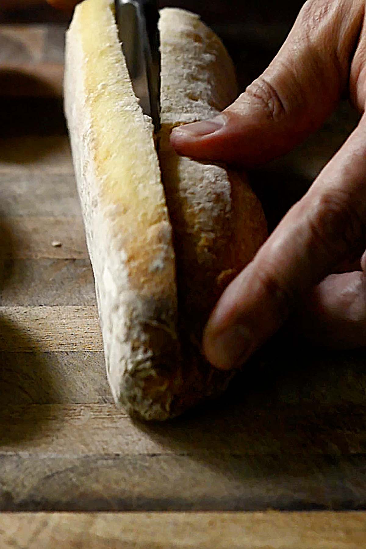 Baguette being sliced for a sandwich.
