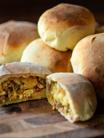 Bacon, sausage, egg, and cheese, breakfast in a bun cut in half revealing the stuffed inside.