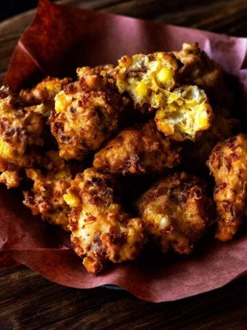Close up of hominy fritters served in a butcher paper lined basket.