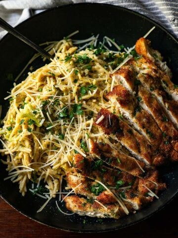 Broccoli Cheddar Pasta with Italian-Style Chicken Cutlet, served in a deep-dish plate.