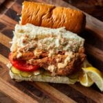 Fried Catfish Po' Boy Sandwich served with coleslaw, fresh tomato, pickles, and remoulade.