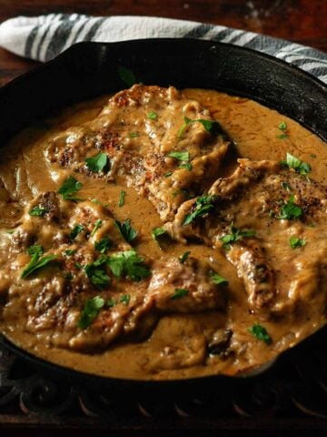 Southern Smothered Pork Chops served in a cast iron skillet on a wooden table.