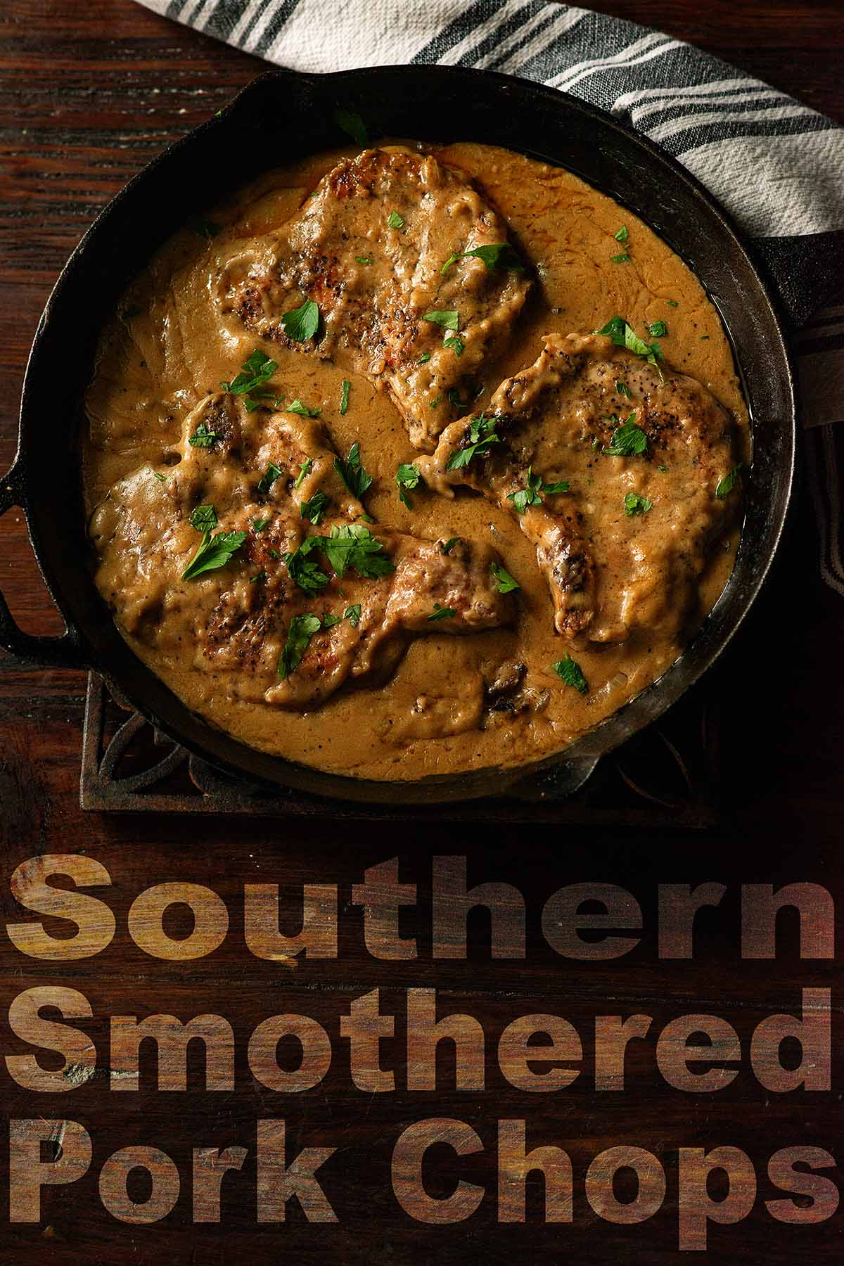 Smothered Pork Chops in a cast iron skillet on a wooden table.