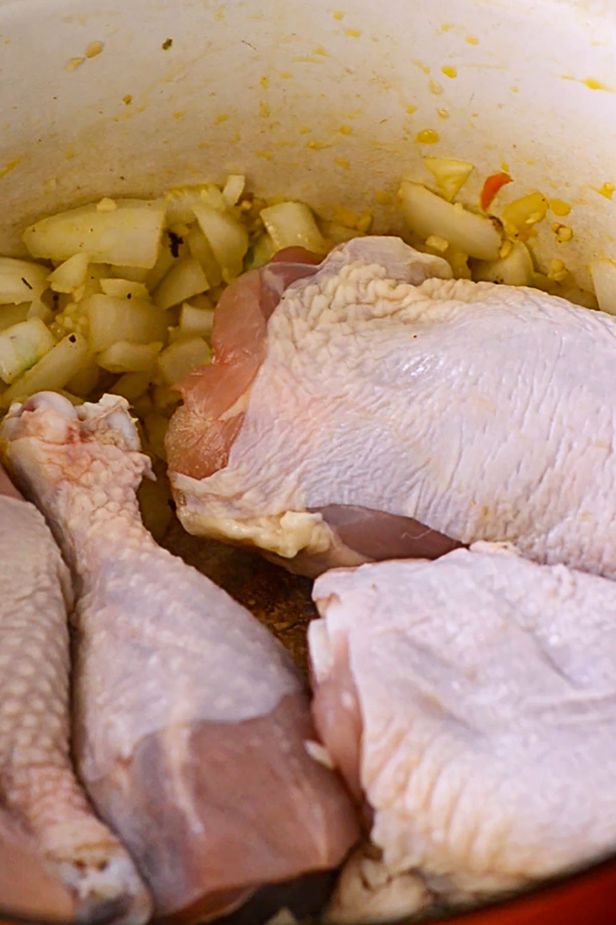 Chicken Legs and Thighs searing in a cast iron Dutch oven.