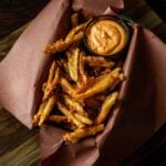Battered and Deep Fried Popeyes copycat french fries served in a butcher paper lined dish with a small bowl of spicy mayo for dipping.