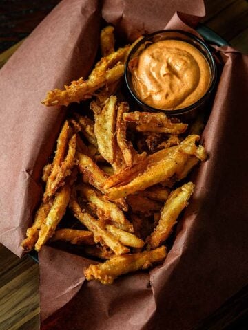 Battered and Deep Fried Popeyes copycat french fries served in a butcher paper lined dish with a small bowl of spicy mayo for dipping.